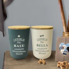 Personalisierte Vorratsdose für Hundeleckerlis mit Namen und Sprüchen auf einer dekorierten Kommode