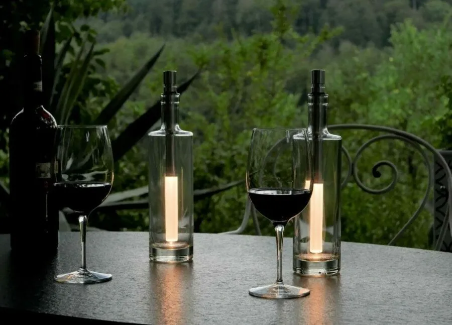 Bottlelight LED Flaschenlampe - 15 lm warmweiß / weiß - Moodbild mit einem Gartentisch, Wiengläsern und grünen Pflanzen im Hintergrund