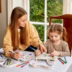 2 Mädchen, die je eine Umhängetasche ausmalen