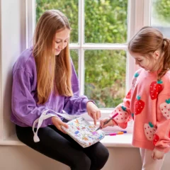 2 Mädchen, die je eine Umhängetasche ausmalen