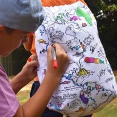 Ein Kind trägt den Turnbeutel auf dem Rücken während ein weiteres Kind Motive auf dem Beutel ausmalt