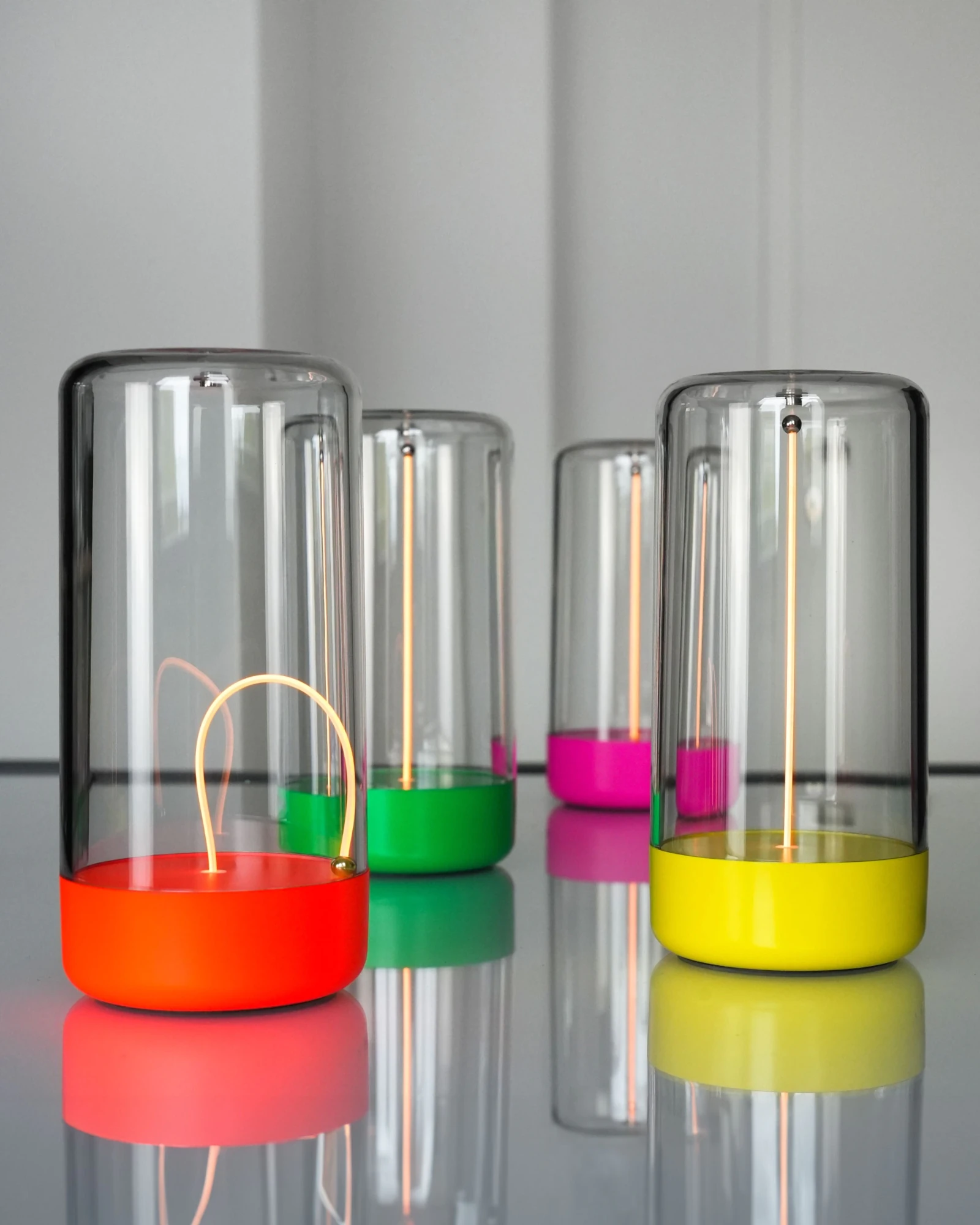 Mehrere Akku-Tischleuchten PULSE by Sompex in verschiedenen Farben auf einer spiegelnden Oberfläche