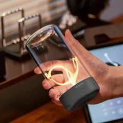 Eine Hand hält die Akku-Tischleuchte PULSE by Sompex über einem Schreibtisch